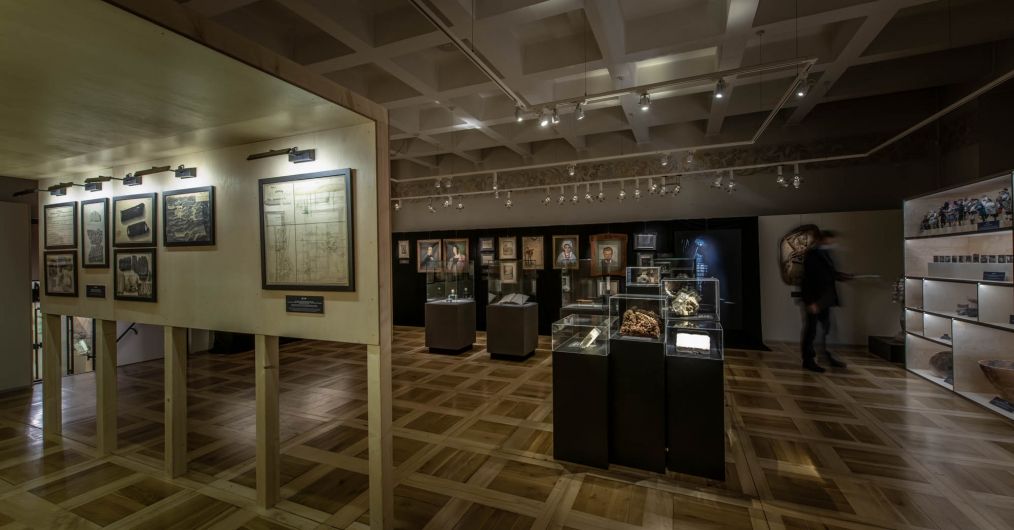 Widok sali wystawowej - drewniana zabudowa, gabloty oraz obrazy