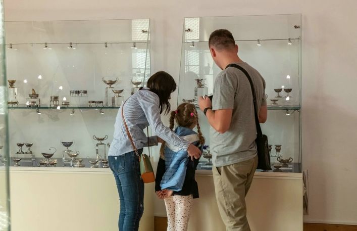 Rodzice wraz z małą dziewczynką oglądają z zainteresowaniem wystawę solniczek.