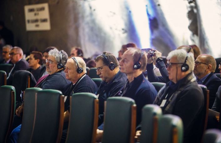 Uczestnicy konferencji siedzą w słuchawkach.