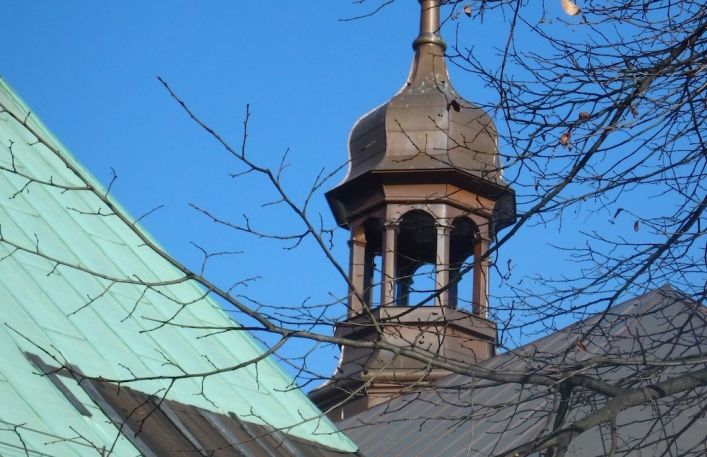 Wieża kościelna z krzyżem nad dachami.