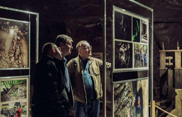 Trzech mężczyzn z uwagą oglądają zdjęcia na wystawie.