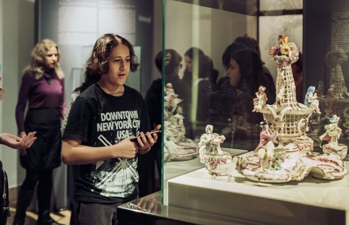Chłopiec ogląda porcelanowy zestaw przyprawowy w gablocie w sali muzeum, w Zamku.