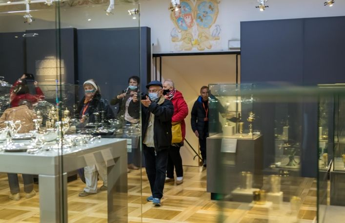 Grupa turystów zwiedza wystawę czasową w Zamku. Część osób fotografuje.