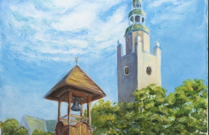 Pejzaż przedstawoiający drewnianą dzwonnicę, wieże zegarową, drzewa w letni dzień i fragmenty murów.