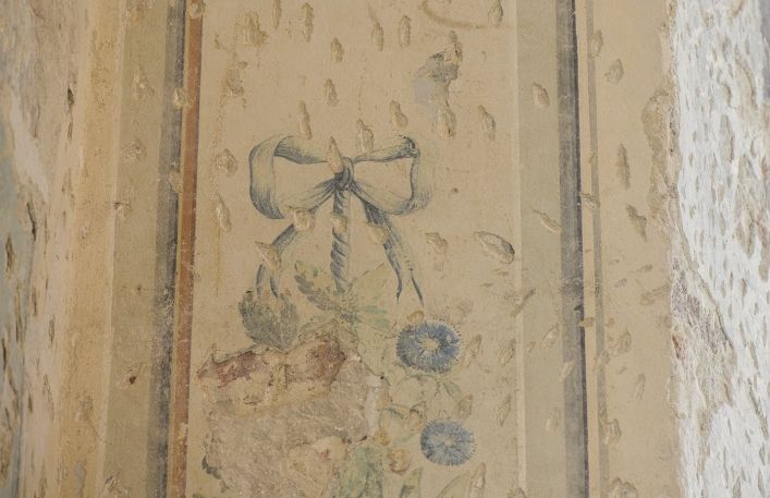 Malowidło na ścianie przedstawiające kokardkę i kwiaty.