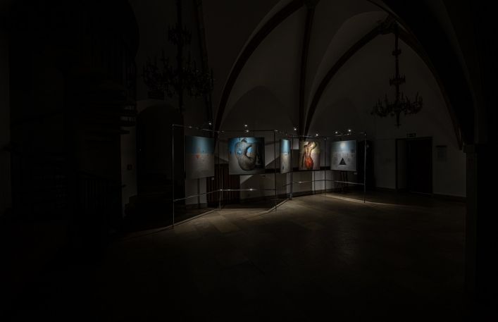 Cykl fotografii obrazów w Sali Gotyckiej w Zamku Żupnym. Na większości prac przedstawiona jest sylwetka kobiety w kolorach niebieskim i beżowym. Dwie fotografie pokazują przyciemnioną salę wystawową
