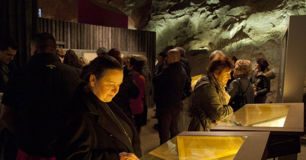 Turyści w ekspozycji podziemnej zapoznają się z dokumentami w gablotach.