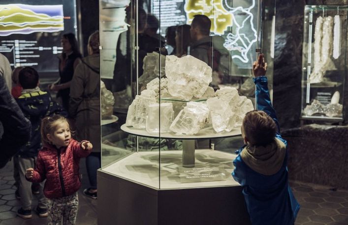 Dwójka małych dzieci pokazuje palcem na kryształy solne w gablocie w podziemnej ekspozycji Muzeum
