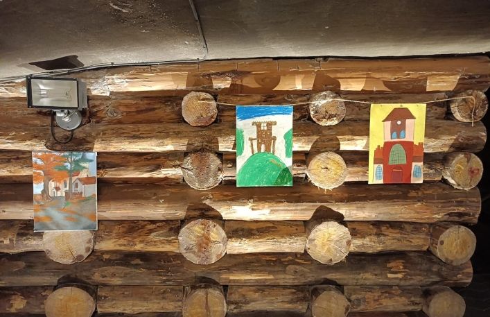 Prace plastyczne powieszone na sznurkach na drewnianych obudowach w sali edukacyjnej w kopalni soli.